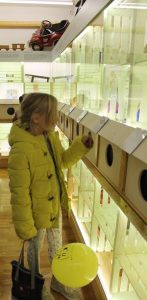 Una visitatrice scopre un giocattolo tastando all’interno di una scatola tattile; accanto ad esso c’è un palloncino giallo.