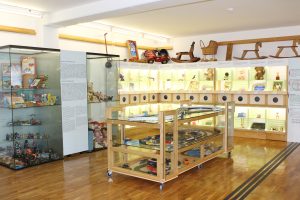 Spazio espositivo con indicazioni tattili, scatole tattili e una vetrina con giocattoli.