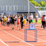Un gruppo di persone di diverse età corre o cammina su una pista di atletica.