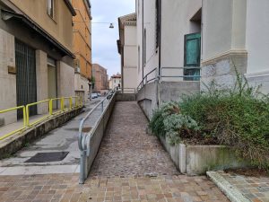 Una rampa di accesso con corrimano metallici conduce all’ingresso dell’edificio.