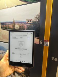 E-reader con audioguida davanti a un pannello informativo sul confine tra Slovenia e Italia.