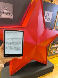 E-reader con un testo sulla mostra davanti a una grande stella rossa a cinque punte nel museo.