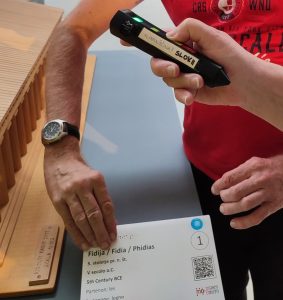 Una persona ascolta una spiegazione con l’etichettatore elettronico Penny Talks accanto al modello tattile di un tempio.